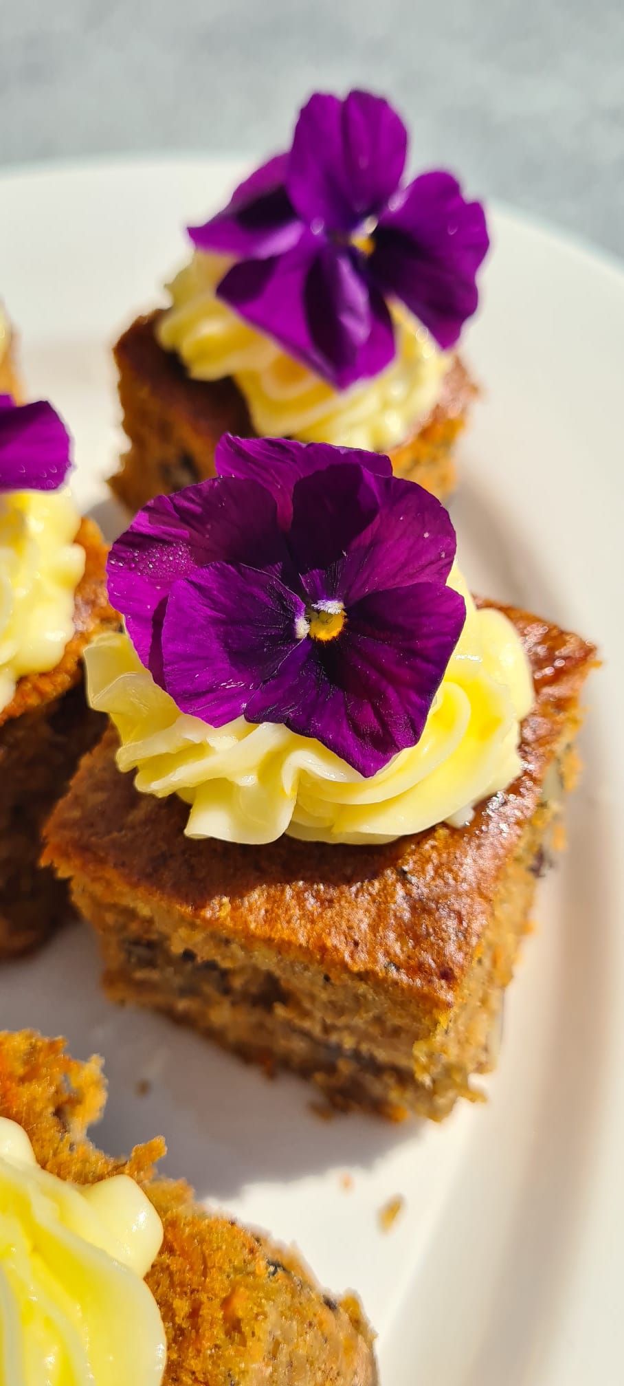 Hausgemachter Karottenkuchen mit Zitronencreme und essbaren Blüten