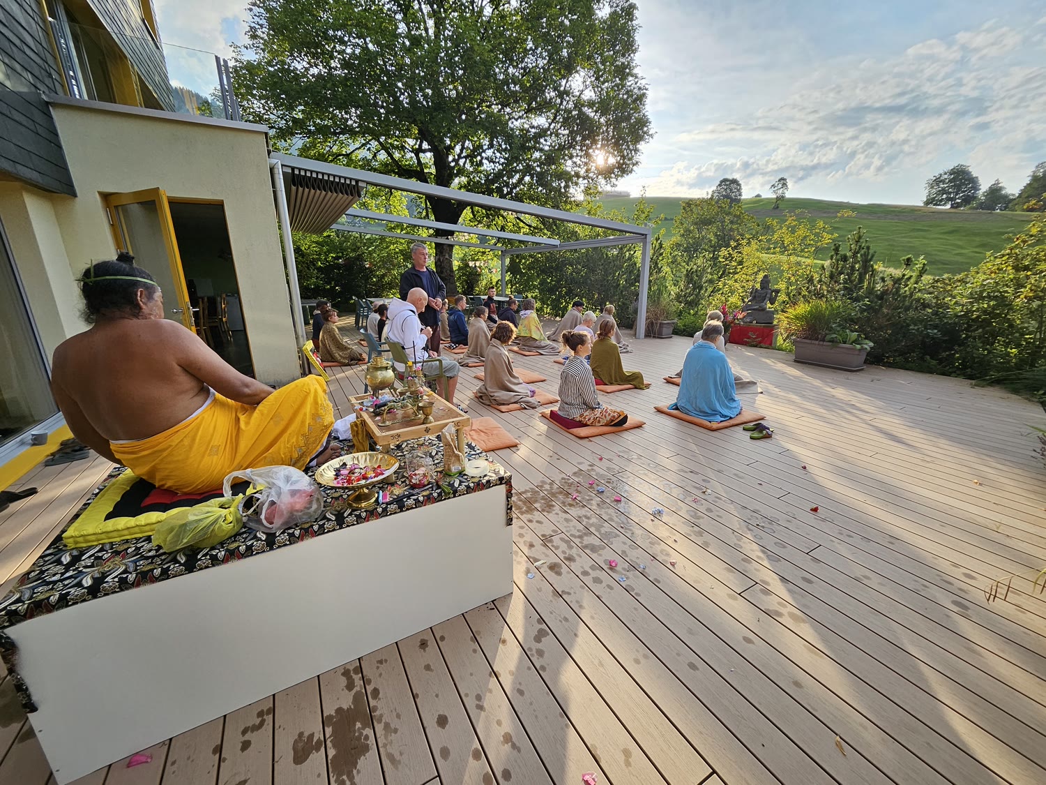 Meditationsgruppe auf der Terrasse des Karunahaus im Morgenlicht mit Blick auf die Toggenburger Hügel